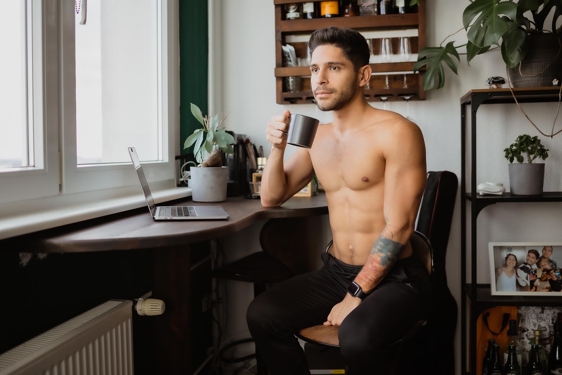 Home Shooting-Mann, Mann mit nackten Oberkörper sitzt am Schreibtisch und trinkt einen Kaffee